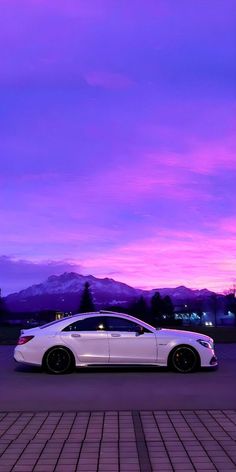 a white car parked in front of a purple sky