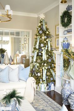 a decorated christmas tree in a living room with blue and white decorations on the walls