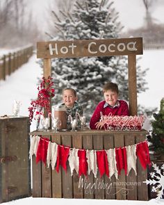 two young boys sitting at a hot cocoa stand in the snow