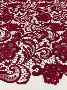 red lace with flowers and leaves is on the tablecloth, it looks like an intricate design