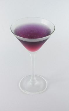 a purple drink in a wine glass on a white background