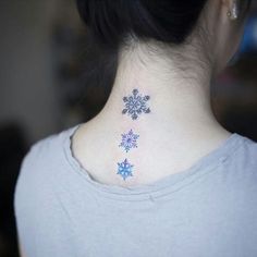 the back of a woman's neck with snowflakes tattooed on her left side