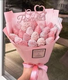 a person holding a bouquet of pink and white chocolates in front of a window