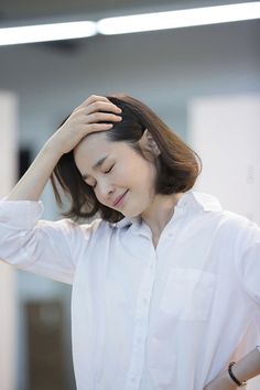 a woman in a white shirt is holding her head