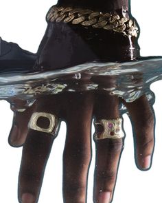 a person's hand with two rings on it, and a skateboard in the water