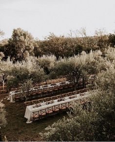 an outdoor wedding set up with tables and white linens in the middle of trees