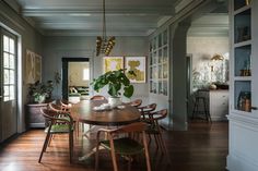 the dining room table is surrounded by wooden chairs and green plant in white vases