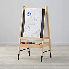 a wooden easel with paint on it in front of a white wall and floor