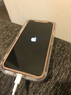 an apple phone is plugged in to a charger on a couch with a cord