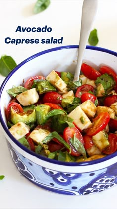 a blue and white bowl filled with vegetables on top of a table next to a spoon