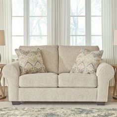 a living room scene with focus on the loveseat and pillows in the foreground