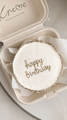 a birthday cake in a white box with writing on the side and gold trimmings