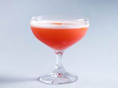 a glass filled with liquid sitting on top of a white table next to an orange slice