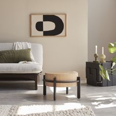 a living room with a white couch and wooden coffee table in front of a painting on the wall