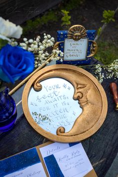 a mirror with writing on it sitting next to some flowers and other things in front of it