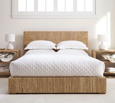 the bed is made up with white linens and wicker headboard, along with two nightstands