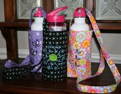 three water bottles sitting on top of a wooden table next to a purse and lanyard