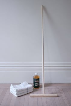 a white broom and some towels on the floor next to a bottle of cleaning agent