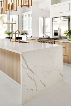 a large kitchen with marble counter tops and wooden cabinetry, along with an island in the middle