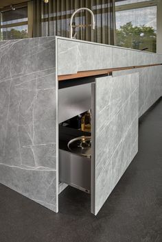 an open cabinet in the middle of a room with grey marble walls and flooring