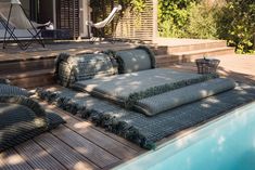 a set of cushions sitting on top of a wooden deck next to a swimming pool