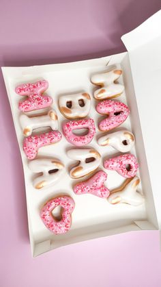 a box filled with donuts covered in pink sprinkles on top of a table