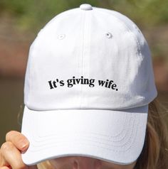 Celebrate your journey to wifedom with our It's Giving Wife Bridal Baseball Hat! This funny bride hat is the perfect accessory for any bride-to-be, whether you're rocking it at your bachelorette party, bridal shower, or just out and about. The playful "It's Giving Wife" embroidery adds a touch of humor and personality, making it a standout piece in your bridal wardrobe. Crafted with high-quality materials and precise embroidery, this bride-to-be cap ensures a comfortable fit and lasting durabili White Wedding Hat (one Size Fits Most), White Wedding Hats One Size Fits Most, White Wedding Hat, One Size Fits Most, White Wedding Hats, One Size Fits Most, Adjustable White Hat For Anniversary, White Curved Brim Baseball Cap For Wedding, Bachelorette Party Accessories, Funny Bride, Bridal Wardrobe