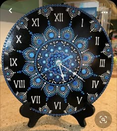 a blue and black clock with roman numerals on it's face sitting on a counter