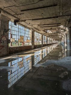 an abandoned building with lots of windows and graffiti on the walls, reflecting in water