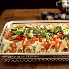 a tray filled with tortillas covered in veggies and sauce on top of a wooden table