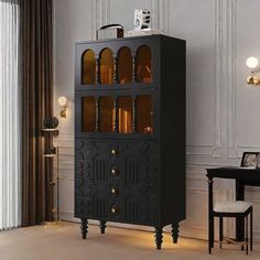 a tall black cabinet with glass doors in a room next to a chair and table