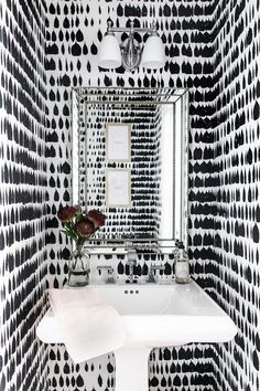 a white sink sitting under a mirror in a bathroom next to a black and white wall