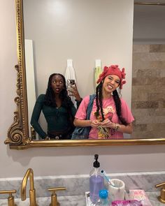 two women standing in front of a bathroom mirror