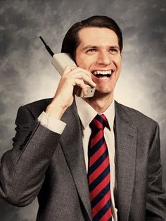 a man in a suit talking on a cell phone with the words business written below him