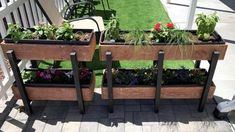 two wooden planters filled with plants on top of a patio