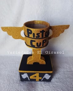 a cup with wings is sitting on top of a black and gold box that says pitt's cup