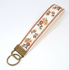 a white strap with orange flowers and gold buckles on an off - white background