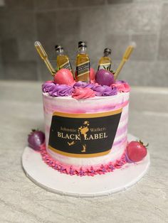 a cake decorated with pink and purple frosting, topped with an assortment of liquor bottles