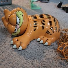 a ceramic cat laying on the floor next to some wires