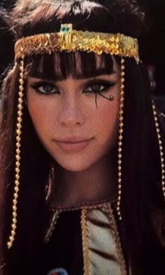 a close up of a person with long black hair and gold jewelry on her head