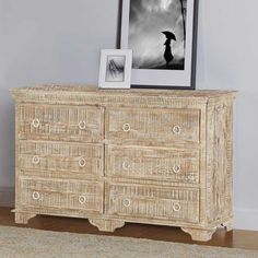 a white dresser with an umbrella on top and pictures hanging above it in front of a gray wall