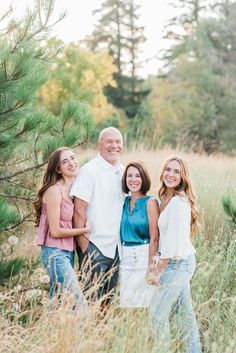 an older man and two younger women standing in tall grass with their arms around each other