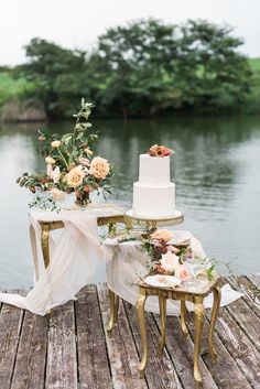 a wedding cake and two chairs on a dock