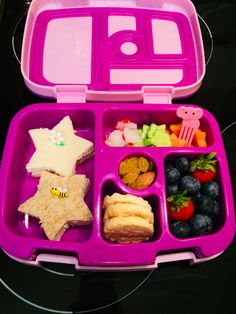 a pink lunch box filled with fruit, crackers and other food on top of a table