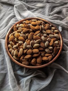 a bowl filled with nuts sitting on top of a gray cloth covered tablecloths