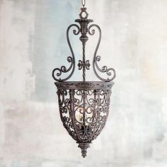 an ornate light fixture hanging from the ceiling in a room with concrete walls and cement flooring