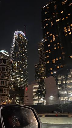 the city lights shine brightly at night in this view from a moving car through traffic