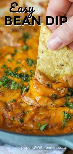 a hand dipping a tortilla chip into a bowl full of salsa and cheese