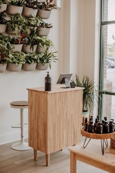 a wooden cabinet sitting in front of a window next to a table with bottles on it