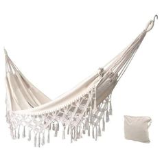 a white hammock with tassels hanging from it's side next to a pillow